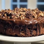 A whole German Chocolate Poke Cake topped with whipped cream, toasted coconut, and chopped pecans, presented in a baking dish.